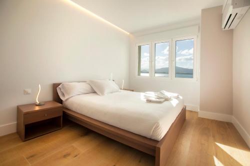 a white bedroom with a bed and a window at Apartamentos Reina Victoria in Santander