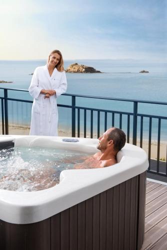 a woman standing next to a man in a hot tub at Hôtel la Baie Valdys Resort & SPA in Douarnenez