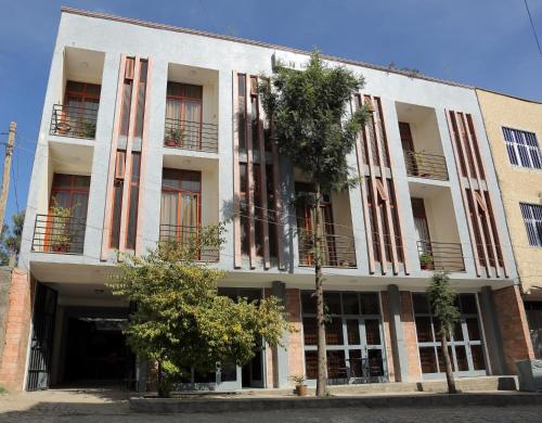 a white building with windows and trees in front of it at Obelisk Hotel Axum in Āksum