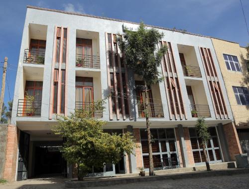 a large white building with a tree in front of it at Obelisk Hotel Axum in Āksum