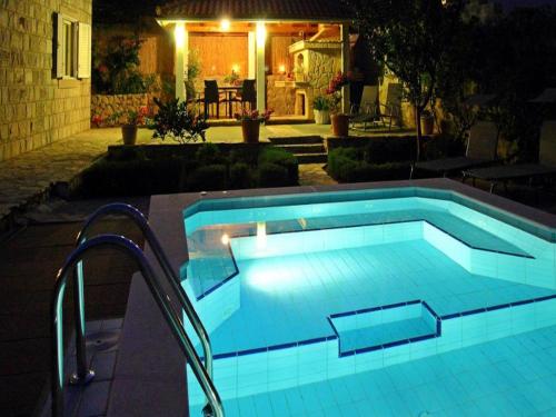 a swimming pool in a yard at night at Villa Aquarius in Čilipi