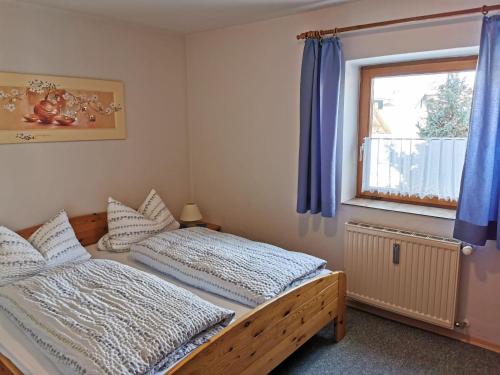 a bedroom with a bed and a window with blue curtains at Ferienhaus-Haidweg-Wohnung-2 in Haidmühle