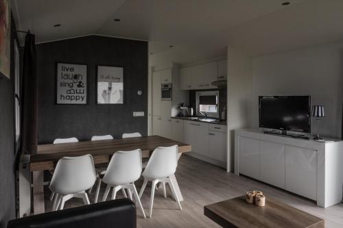 een woonkamer met een eettafel en witte stoelen bij CS 34 - Vakantiepark Callassande in Callantsoog