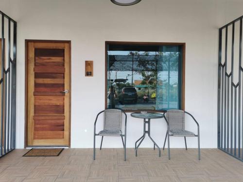 une table et deux chaises devant une porte dans l'établissement Nararin Garden House, à Ban Nong Srah