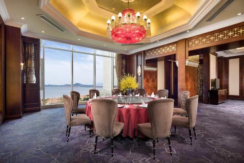 a dining room with a table and chairs and a chandelier at Crowne Plaza Ocean Spring Resort by IHG in Jimo