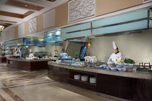 a chef preparing food in a restaurant kitchen at Crowne Plaza Ocean Spring Resort by IHG in Jimo