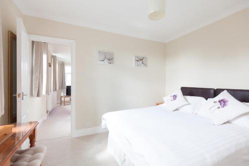 a white bedroom with a large white bed with pillows at Toothbrush Apartments - Ipswich East - Cauldwell Ave in Ipswich