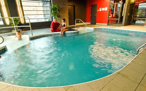 two people sitting in a large swimming pool at Grand Times Hotel Sherbrooke in Sherbrooke
