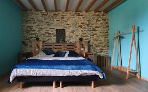 ein Schlafzimmer mit einem Bett und einer Steinmauer in der Unterkunft Bed and Breakfast au Champ du Douits in Saint-Agnan-le-Malherbe