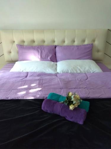a purple bed with purple pillows and flowers on it at Captain's Cabin Resort - Naval Heritage (Swimming Pool) in Kota Bharu