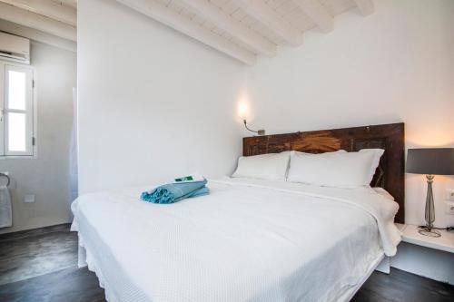 Un dormitorio blanco con una cama grande con una bolsa azul. en On The Rocks en Symi