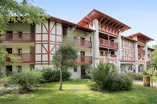 an apartment building with red balconies and a yard at Résidence Pierre & Vacances Le Domaine de Gascogne in Biscarrosse