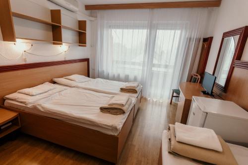 1 dormitorio con 2 camas, escritorio y ventana en Tisza Sport Hotel en Szeged