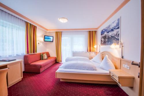 a hotel room with a bed and a couch at Hotel Grundlhof in Bramberg am Wildkogel