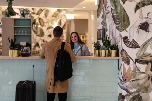 un homme debout devant un comptoir avec une femme dans l'établissement Holiday Inn - the niu, Crusoe Bremen Airport by IHG, à Brême