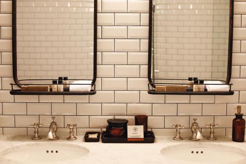 a bathroom with two sinks and two mirrors at Rooms Hotel Tbilisi in Tbilisi City