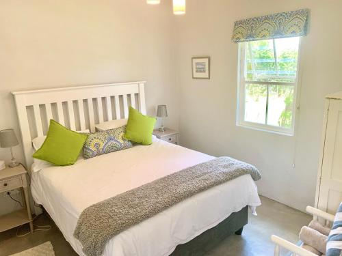 um quarto com uma cama com almofadas verdes e uma janela em Paul Wallace Wines & Cottages em Elgin