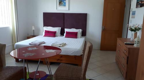 a bedroom with a bed with pink pillows and a table at Sacha Tourist Residence 2 in Mahébourg