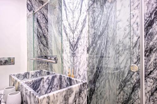 bagno con doccia in marmo e porta in vetro di Hola Lisbon Suites a Lisbona