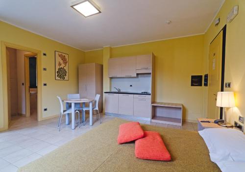 ein Wohnzimmer mit einer Küche und einem Tisch mit roten Kissen in der Unterkunft Castellaro Golf Resort in Castellaro