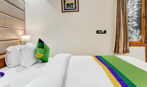 a bedroom with a white bed with a green pillow at Hotel Sun Grand in Dehradun