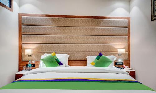 a bedroom with a large bed with green pillows at Hotel Sun Grand in Dehradun