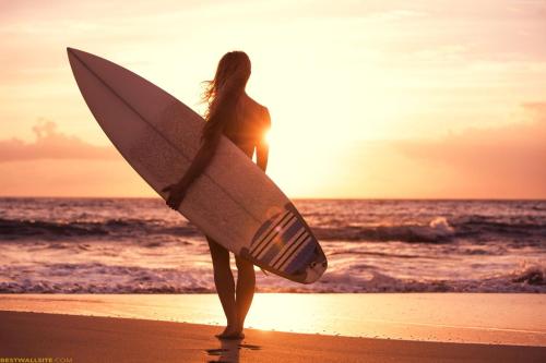 uma mulher parada na praia segurando uma prancha de surf em Amazing Villa em Matara
