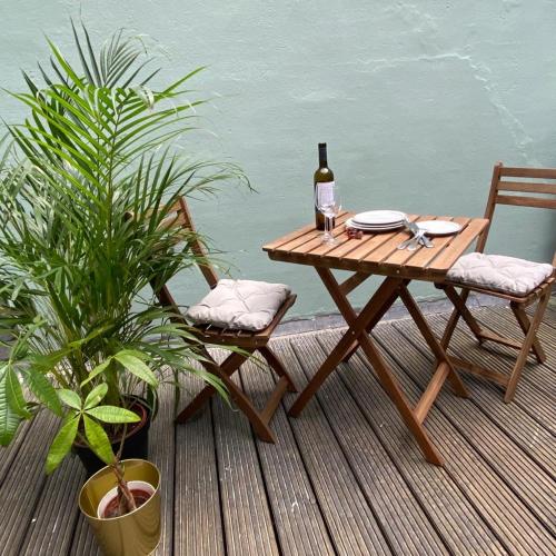a wooden table with a bottle of wine and two chairs at Apartement City Centre with roof terrace and parking with additional costs in The Hague