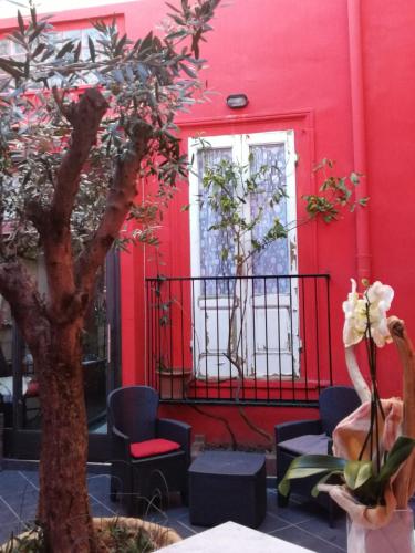 a red building with a tree and chairs and a window at Al 20 Guest House Fiera Milano - Certosa - San Siro in Milan