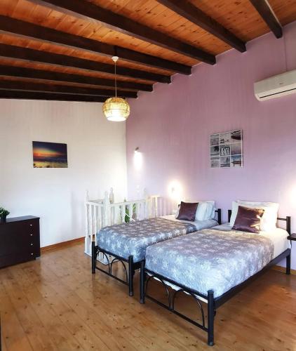 two beds in a room with pink walls and wooden ceilings at Villa PANGALIS Romantica in Kato Pavliana