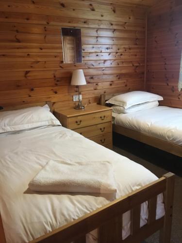 two beds in a room with wooden walls at Chalet in Tyndrum