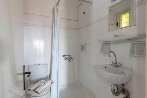 a white bathroom with a shower and a sink at Margarita Apartments in Ierápetra