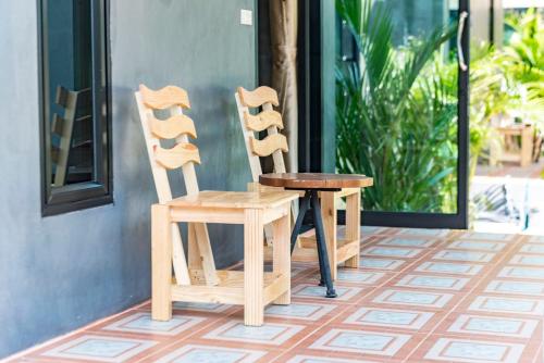 two wooden chairs and a table on a porch at Hanoii House in Ko Mak