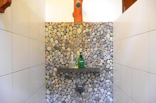 a bathroom with a shower with a stone wall at Cocotinos Sekotong Lombok in Sekotong