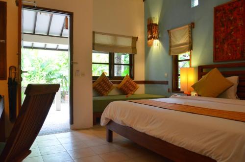 a bedroom with a bed and a couch and windows at Cocotinos Sekotong Lombok in Sekotong