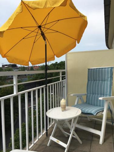 a yellow umbrella on a balcony with a chair and a table at Komfort Hotel Ludwigsburg in Ludwigsburg