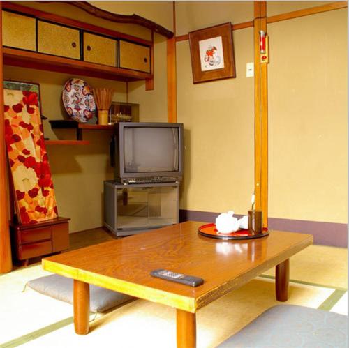 a living room with a coffee table and a tv at Daiya Ryokan in Kyoto