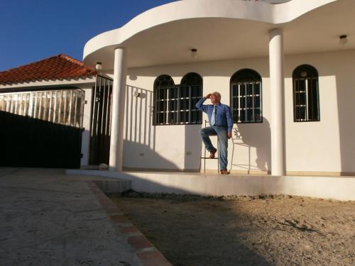a man sitting on a chair in front of a house at Guesthouse Villa La Isla in La Romana