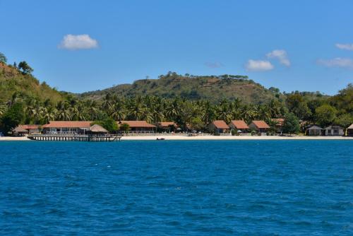 a resort on a beach with palm trees and blue water at Cocotinos Sekotong Lombok in Sekotong