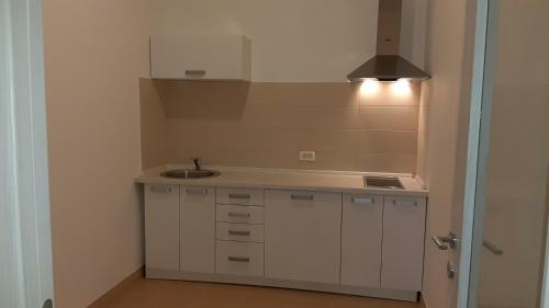 une petite cuisine blanche avec évier et lumière dans l'établissement Villa Roan, à Bar