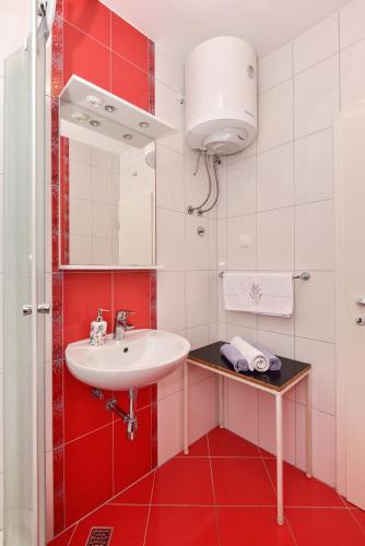 a red and white bathroom with a sink and a mirror at Apartments Makarska Gudelj Cvitan in Makarska