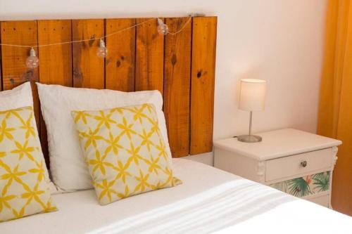 - une chambre avec un lit doté d'oreillers jaunes et blancs dans l'établissement GATU Villa Bani con terraza y vista frontal al mar, à Cadix
