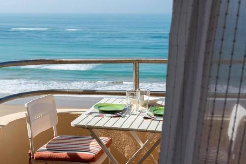 einen Tisch und Stühle auf einem Balkon mit Meerblick in der Unterkunft GATU Villa Bani con terraza y vista frontal al mar in Cádiz