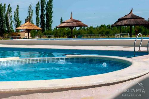 a swimming pool with umbrellas in a resort at Cabañas Morita Mia in San Rafael