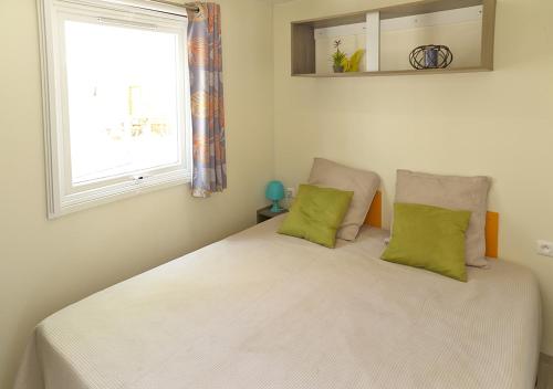 a bedroom with a white bed with two green pillows at Camping San Damiano in Biguglia
