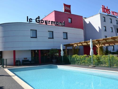 a hotel with a swimming pool in front of a building at ibis Europe Chalon Sur Saone in Chalon-sur-Saône