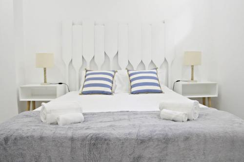 ein weißes Bett mit blauen und weißen Kissen darauf in der Unterkunft Cais - Waterfront Holiday Apartments - By SCH in São Martinho do Porto