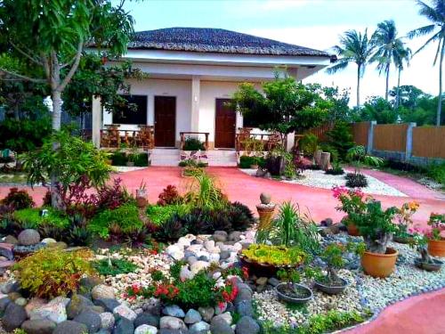 a garden with flowers and plants in front of a house at Adayo Cove Resort in Siquijor