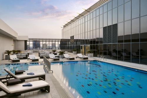 a large swimming pool in a building with lounge chairs at The Hotel Galleria Jeddah, Curio Collection by Hilton in Jeddah