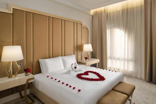 a hotel room with a bed with a red flower on it at The Hotel Galleria Jeddah, Curio Collection by Hilton in Jeddah
